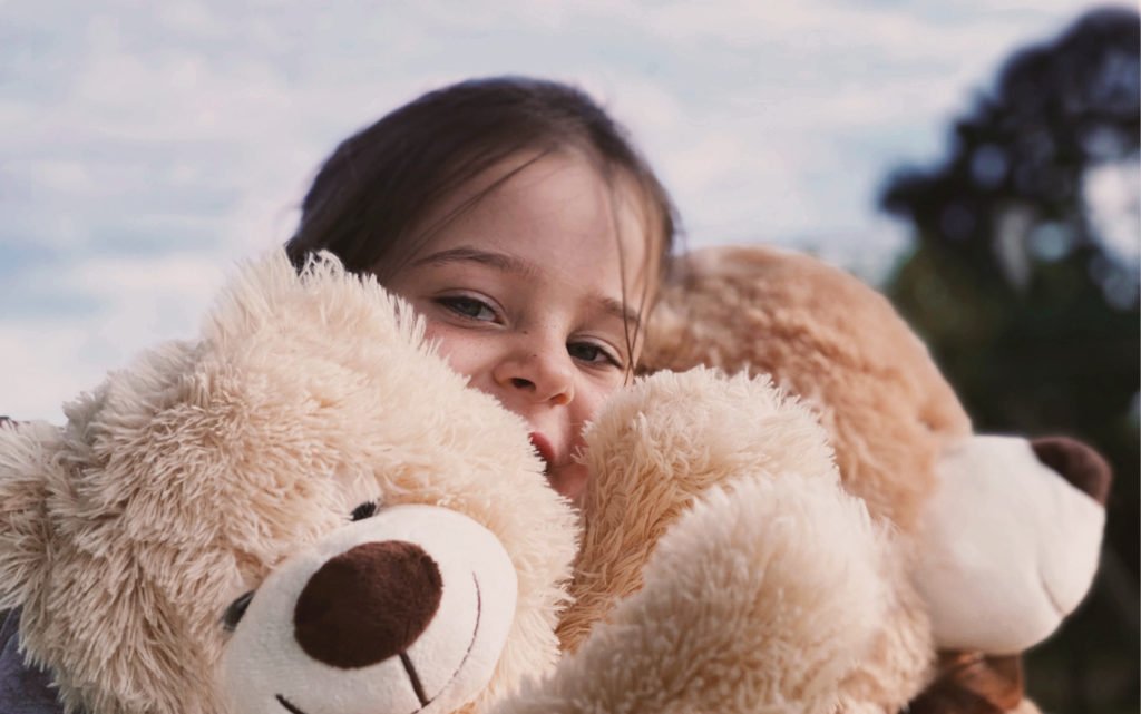 Plüsch Mädchen guckt zwischen zwei Teddys hindurch